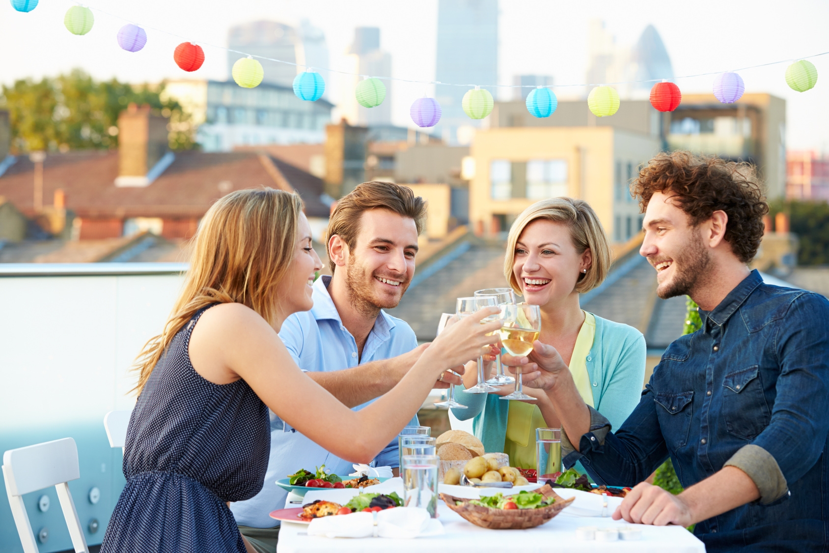 Group Of Friends Eating Meal On Rooftop Terrace